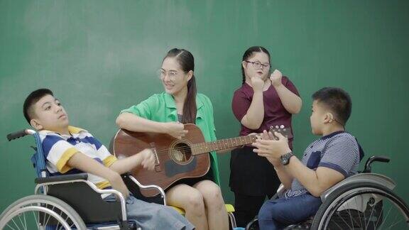 组亚洲残疾儿童在轮椅和自闭症演唱活动老师在教室弹吉他提高学习技能的活动贫困儿童教育