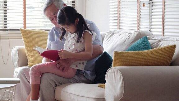 快乐的小女孩和爷爷在家里读故事书香港的家庭