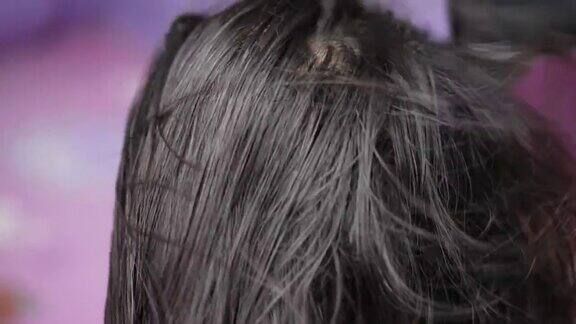 一位中年亚洲妇女在家里用吹风机吹头发