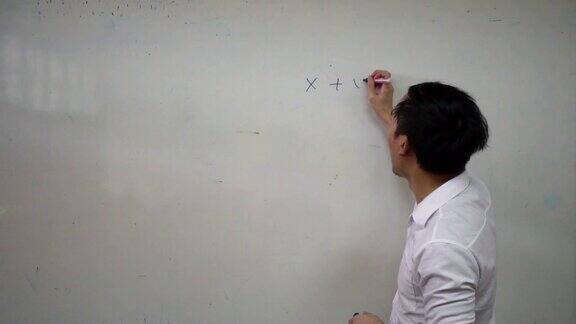 年轻英俊的亚洲数学老师正在白板上写数学公式教育与办学理念