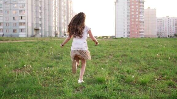 小女孩在城市荒地的草地上奔跑