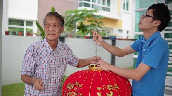 亚洲华人父亲和儿子准备大红灯笼在他们家的前院在中国新年前夕