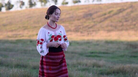 年轻的乌克兰妇女穿着传统的民族刺绣衬衫和裙子走在牧场上附近有放牧的奶牛