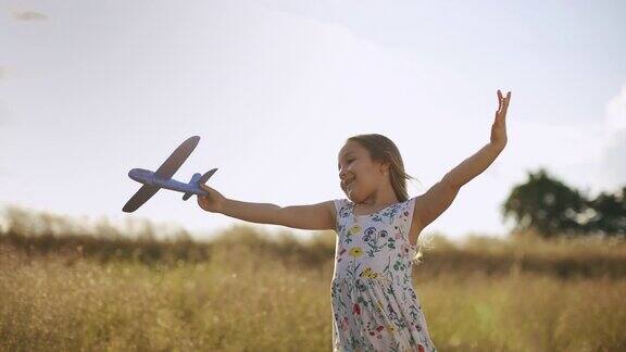 日落时分美丽的小女孩和她的飞机玩具在草地上奔跑慢动作