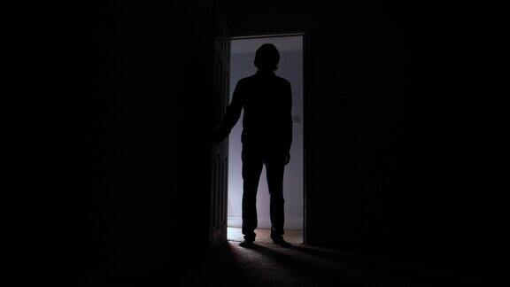 一个男人打开门走进了黑暗的房间剪影