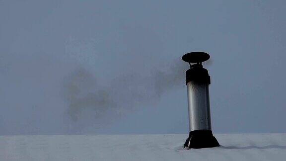 灰色的铁烟囱里有很多烟灰冬天的天空就在后面