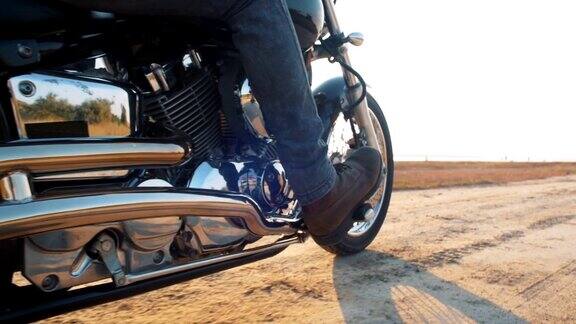 近距离拍摄的摩托车手驾驶他的摩托车在道路上日落