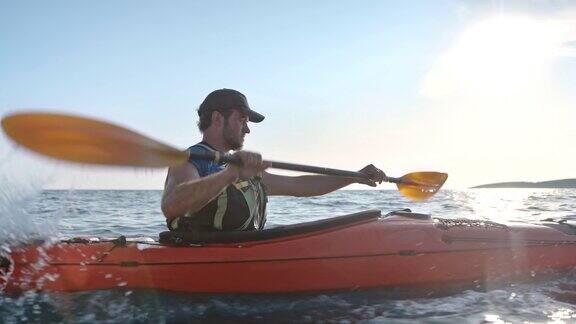 SLOMO男性皮划艇运动员在阳光下穿过平静的海面