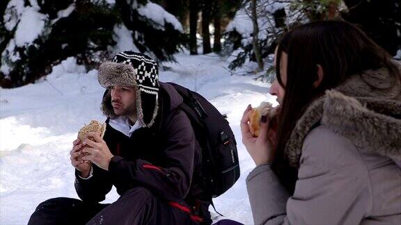 年轻夫妇在滑雪中休息吃三明治