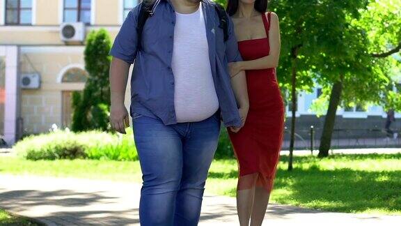 漂亮苗条的女人穿着红裙子牵着肥胖的男友梦想