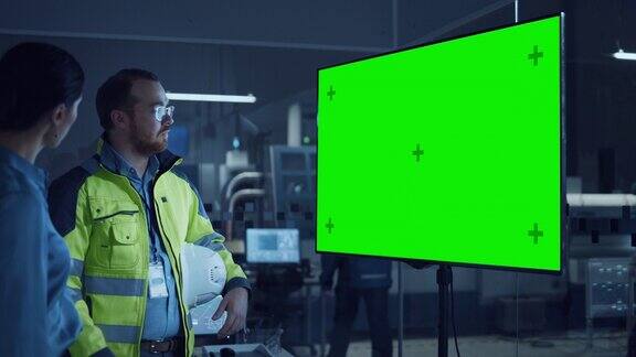 办公室会议:自信的女项目经理到总工程师观看交互式数字白板电视显示绿屏色度键显示与机械工厂慢动作的手势