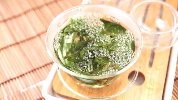 将中国绿茶从玻璃壶倒入小杯子中近距离选择聚焦