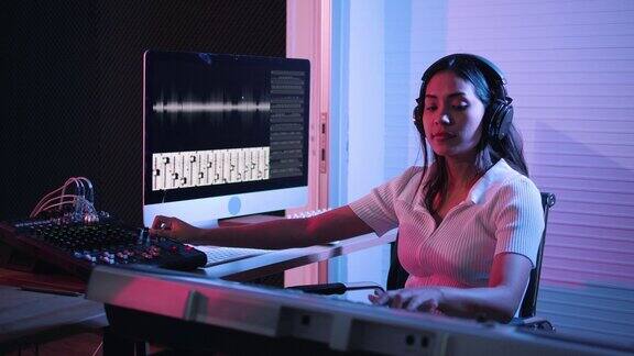 音乐制作工作室生产商在录音棚工作的妇女用电脑和混音器在录音棚创作音乐音乐制作