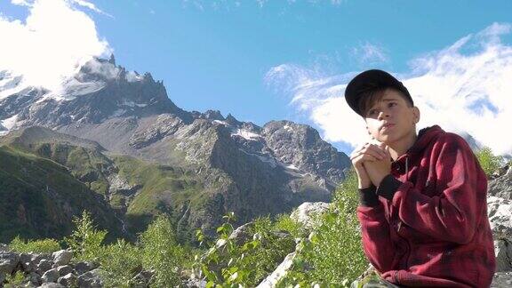 一个少年坐在岩石上看山