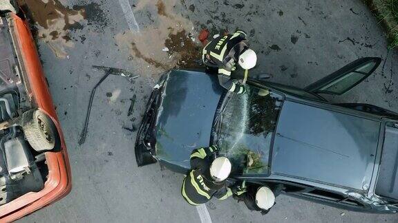 在一场车祸现场两名消防员划破了一辆撞毁的汽车的挡风玻璃
