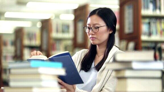 年轻的韩国女子在图书馆看书做研究