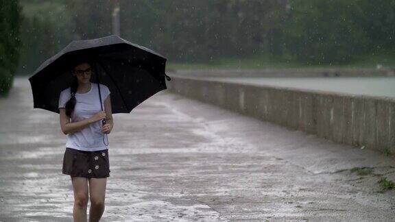 女孩撑着伞在雨天独自走在街上
