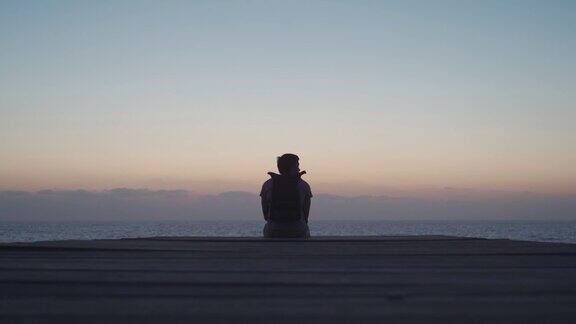 一个背着背包的男子在塞浦路斯岛的木制码头上欣赏日落和地中海的景色自由喜欢旅游男性欣赏日落独自旅行