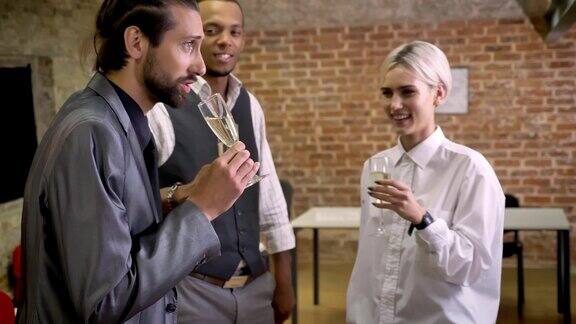 三个多民族的员工在办公室跳舞在玻璃杯里唱歌喝香槟公司派对