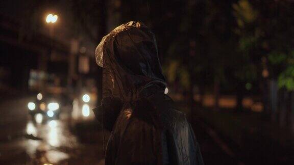 当下雨的时候年轻的商人穿上雨衣走在城市外面的雨中