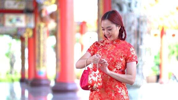 穿着红色旗袍的年轻亚洲美女的肖像对着镜头微笑做着中国人的问候手势美丽快乐的女孩在做祝贺的手势