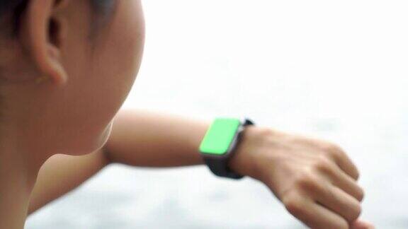 女人慢跑和检查脉搏的智能手表绿色屏幕