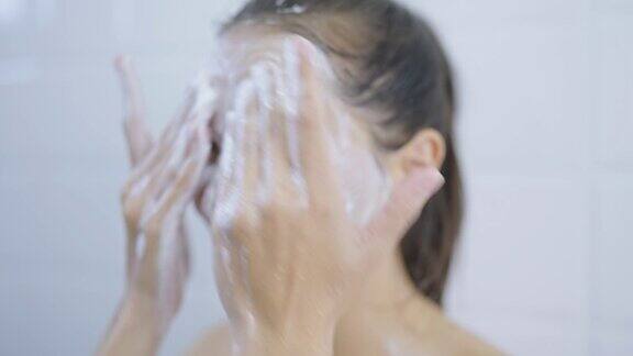 女人在浴室里用泡沫洗脸