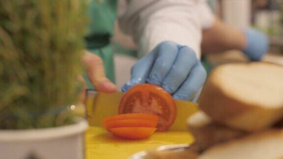 厨师的手用刀将西红柿切成圆形的薄片和薄片