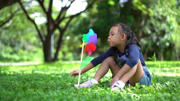快乐的亚洲小女孩在花园里玩纸风车