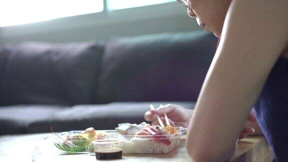 亚洲妇女吃日本食物从外卖服务为外卖在家