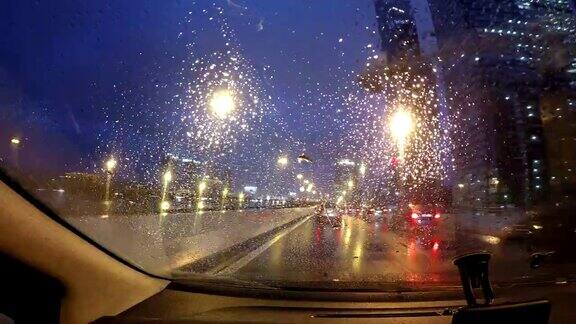 夜雨在城中行驶时光流逝夜晚的道路POV透过挡风玻璃看雨点在夜晚的城市时光流逝