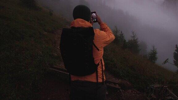 男子摄影师徒步旅行在一个寒冷的雾蒙蒙的日落高山白云石