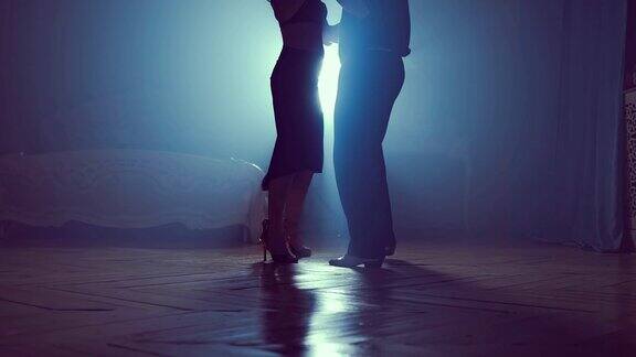 男人和女人在舞蹈中跳舞缓慢的运动在烟雾弥漫的黑暗房间里的剪影