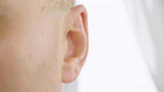 成年男性的耳朵靠近男人在动他的耳朵耳鼻喉科和听力健康