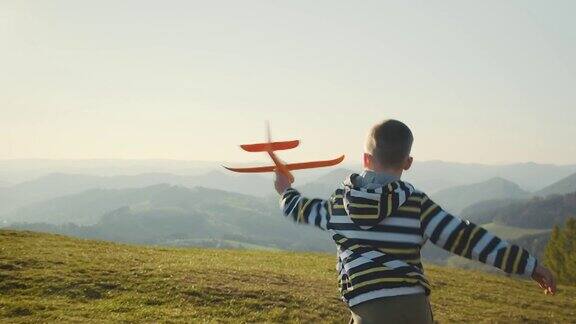 快乐的旅行者男孩在阳光明媚的一天在公园玩飞机玩具4K慢动作视频日落时分孩子在山顶上奔跑宇宙边缘之旅