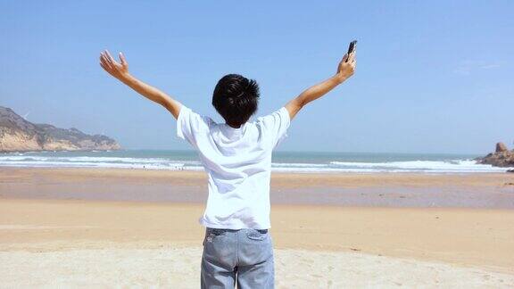 一个人举起双手在海边享受自由