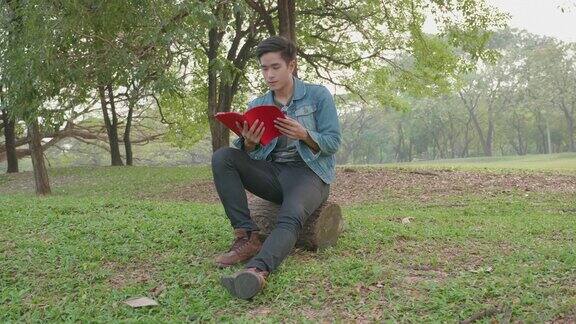 一个年轻的亚洲人在公园里看书