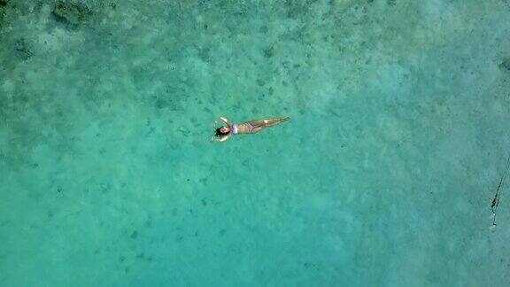 鸟瞰图一个迷人的女人在比基尼漂浮在水晶清澈的海洋一个美丽的女孩在印度洋游泳