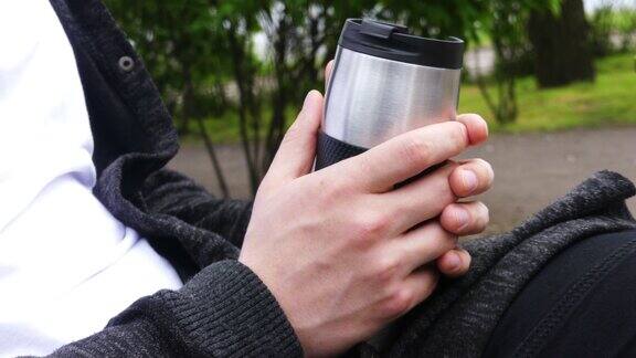 在户外喝茶或喝咖啡年轻人拿着热杯杯子罐子在公园喝茶或咖啡主题旅行或娱乐