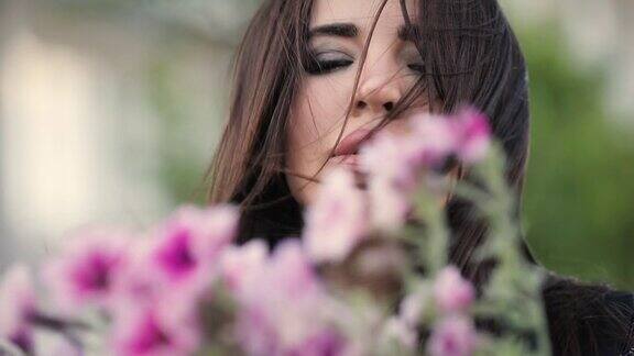 性感迷人的女人嗅美丽的花在花园里