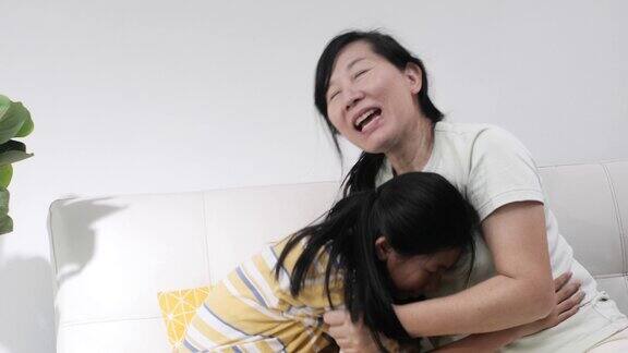 快乐的亚洲女孩拥抱她的母亲坐在一起在家里生活理念