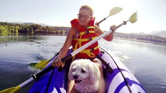 女孩和宠物狗划着皮划艇穿过一个湖
