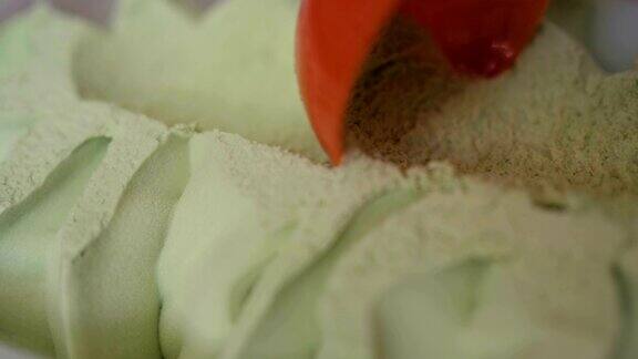 开心果冰淇淋正在被挖近缓慢的运动绿色冰淇淋的特写镜头红色勺子的冰淇淋