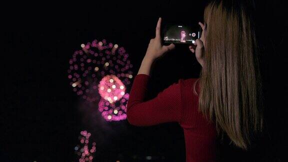 她正在用手机拍摄新年庆祝活动结束时的烟花