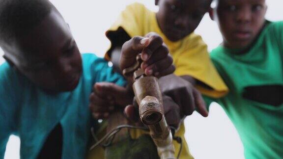 特写的年轻黑人非洲男孩等待水在一个公共的水龙头水龙头水危机贫困干旱气候变化全球变暖