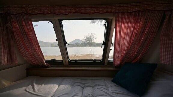 在房车的空卧室里透过窗户可以看到早晨湖边的景色