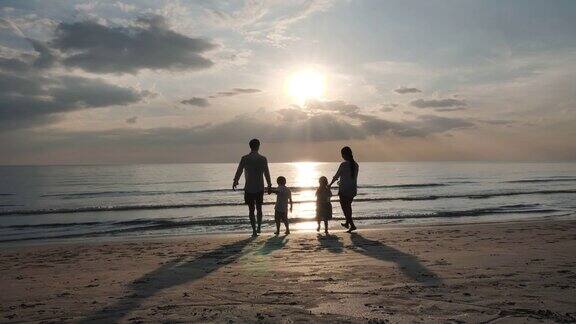 快乐的亚洲家庭在暑假父亲母亲儿子和女儿牵着手一起跑到海边背景夕阳在海上放松假期和旅游慢动作
