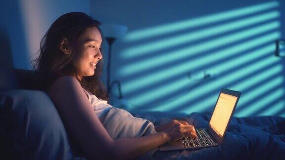 女人晚上在床上用笔记本电脑