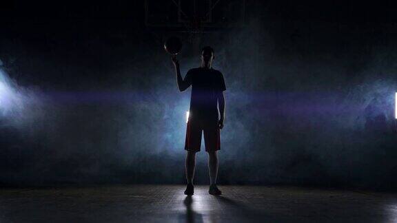 篮球运动员在黑暗的体育馆和烟雾中表演不同的技巧和旋转球慢动作