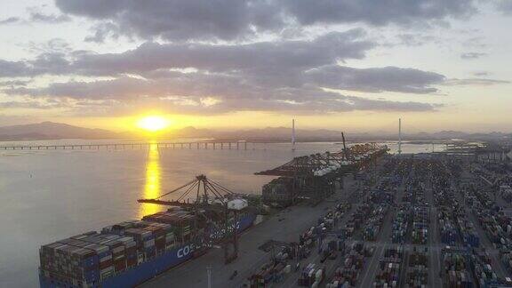 夕阳下几艘大型货轮停在港口装卸集装箱